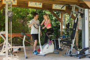 a man and a woman riding on a exercise bike at Les Carmes and spa in Le Thor