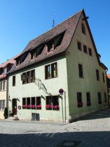 ein großes weißes Gebäude mit braunem Dach in der Unterkunft Pension Hofmann-Schmölzer in Rothenburg ob der Tauber