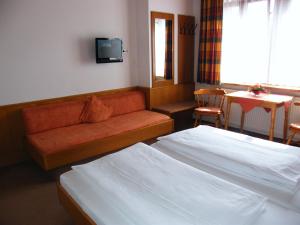 ein Hotelzimmer mit 2 Betten, einem Sofa und einem Tisch in der Unterkunft Pension Hofmann-Schmölzer in Rothenburg ob der Tauber