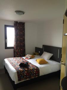 a bedroom with a bed with a cat laying on it at Kyriad Direct La Rochelle Aytré in Aytré