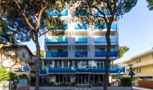 un edificio de apartamentos con balcones azules y árboles en Hotel Desire', en Riccione