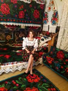 una mujer sentada en un sofá en una habitación con mantas en Pension Bud, en Onceşti