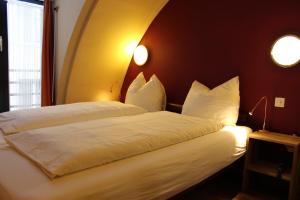 a bedroom with a bed with white sheets and pillows at Hotel Falken in Lucerne