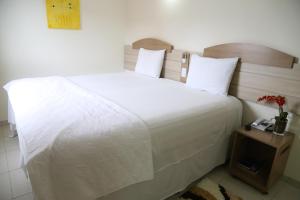 a bedroom with a large white bed and a night stand at Larison Hotéis - Porto Velho in Porto Velho