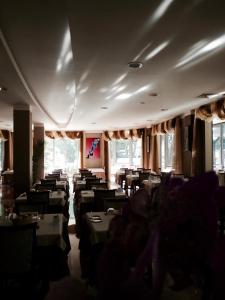 una sala da pranzo con tavoli, sedie e finestre di Hotel Gambrinus a Lido di Jesolo