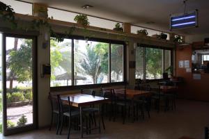 a restaurant with tables and chairs and large windows at Arava Hostel in Eilat