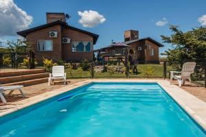 a swimming pool with a house in the background at Cabañas & Suites Vista Hermosa in Los Reartes