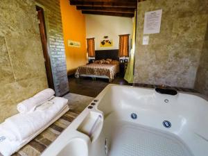 a bathroom with a bath tub and a bedroom at Cabañas & Suites Vista Hermosa in Los Reartes