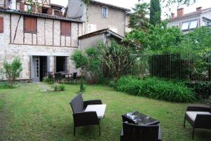 a yard with chairs and tables and a building at Le Clos Saint Paul in Figeac
