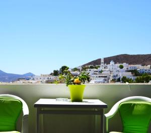 een tafel met stoelen en een gele vaas op een balkon bij Georgios Milos in Adamas