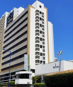 Un grand bâtiment blanc avec un panneau devant. dans l'établissement Pisa Plaza Hotel, à Salvador