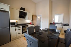 eine Küche mit einem schwarzen Tisch und Stühlen sowie eine Küche mit einem Tisch in der Unterkunft Cider House in Ulverston