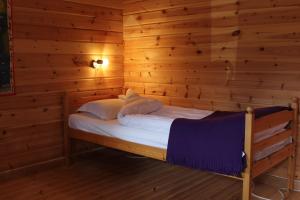 1 dormitorio con 1 cama en una habitación de madera en Höglunda Gård B&B Lantgård, en Skanderåsen