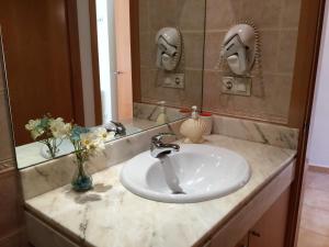 W łazience znajduje się umywalka i lustro. w obiekcie Duplex Playa de Rons w mieście O Grove