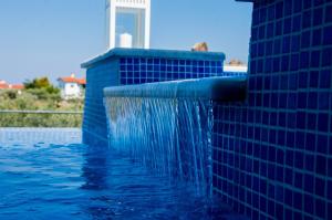una piscina con parete piastrellata blu e cascata d'acqua di Xalonia Villas a Agios Nikolaos
