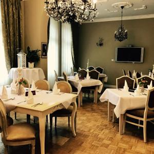 een eetkamer met witte tafels en stoelen en een tv bij Hotel Amalia in Kudowa-Zdrój