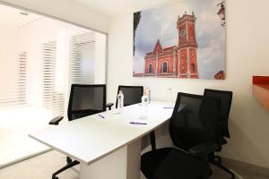 um escritório com uma secretária branca e cadeiras em One Queretaro Plaza Galerias em Querétaro