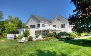 a large white house with a white chair in the yard at Reluctant Panther Inn & Restaurant in Manchester