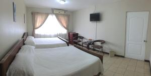 a bedroom with a bed and a dresser at Hotel Santa Maria Inn in Alajuela