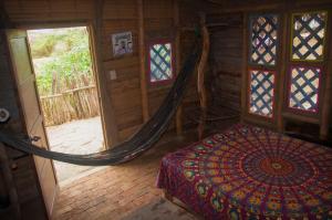 1 dormitorio con 1 cama y 1 hamaca en una habitación en Grillo Tres Puntas Eco-Hostel, en Zorritos