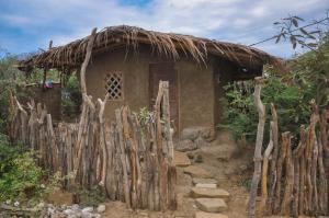 una pequeña casa con techo de paja y valla en Grillo Tres Puntas Eco-Hostel, en Zorritos