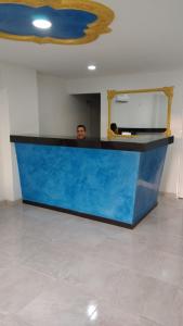 a man standing behind a blue counter with a mirror at Hotel El Imperio in Santa Marta