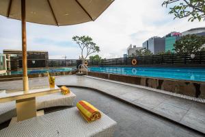 - une piscine avec 2 chaises et un parasol dans l'établissement The Arista Hotel Palembang, à Palembang