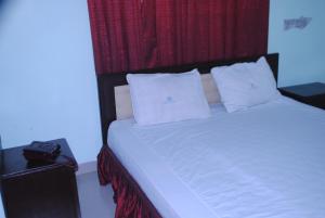 1 dormitorio con cama blanca y cortina roja en Shopno Bilash Holiday Suites, en Cox's Bazar
