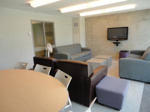 a waiting room with couches and tables and a tv at Lakehead University Residence and Conference Centre in Orillia