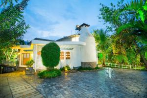 a white house with a fence and trees at Mistletoe Homestay & Cafe in Munnar