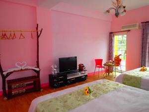 a pink room with two beds and a tv at Flower Tamura in Guanshan