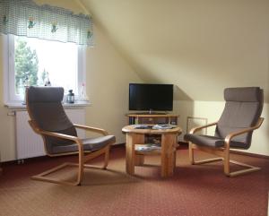 dwa krzesła i stół w salonie z telewizorem w obiekcie Fewo's Kiekut w mieście Lohme