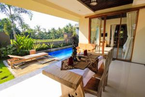 a patio with a table and chairs and a pool at AS Resort in Ubud