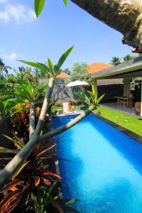 a pool with palm trees in front of a house at AS Resort in Ubud