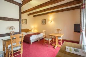 a bedroom with a bed and a desk and a table at Hostellerie Schwendi in Kientzheim