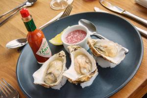 a plate with three oysters and a bottle of sauce at Eslington Villa in Gateshead