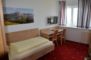 a bedroom with a desk and a bed and a table at Gasthof-Pension Urzn in Altmünster
