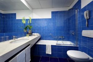 a blue tiled bathroom with a toilet and a tub at Eurostars Monte Tauro in Taormina