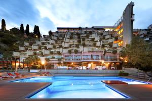 un hotel con piscina di fronte a un edificio di Eurostars Monte Tauro a Taormina