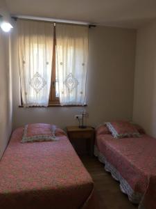 1 dormitorio con 2 camas y una ventana con cortinas en Apartaments Alt Aneu Baqueira, en Isavarre