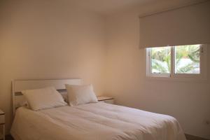 a bedroom with a white bed with a window at 3C Jardín del Río in Costa Calma