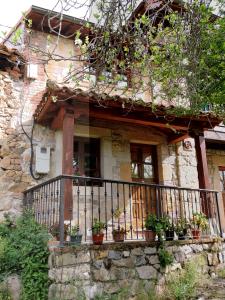 a stone house with a balcony with potted plants at Ablanera 2 in Cangas de Onís