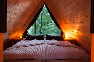 a bed in a wooden room with a large window at Glamping Savinja in Ljubno