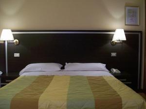 a bedroom with a large bed with two lamps at Hotel La Rosta in Reggio Emilia