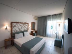 a bedroom with a large bed and a window at Long Beach Hotel & Resort in Lóngos