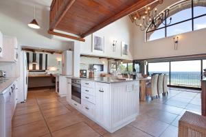 a kitchen with white cabinets and a view of the ocean at Whale Huys Luxury Oceanfront Eco Villa in Gansbaai