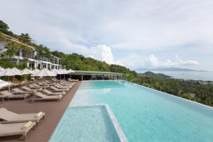 a large swimming pool with lounge chairs and the ocean at Mantra Samui Resort - Adults Only in Mae Nam