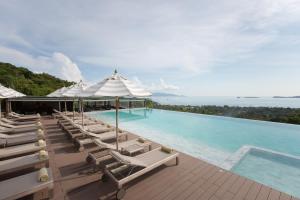 a pool with chaise lounge chairs and an ocean view at Mantra Samui Resort - Adults Only in Mae Nam