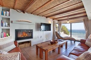 un soggiorno con divano, tavolo e camino di Whale Huys Luxury Oceanfront Eco Villa a Gansbaai