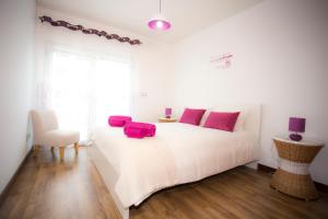 a white bedroom with a large white bed with pink pillows at Surf and Stones Apartment in Peniche
